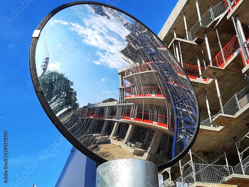 a condominium construction site viewed through the reflection in a convex mirror on a sunny day