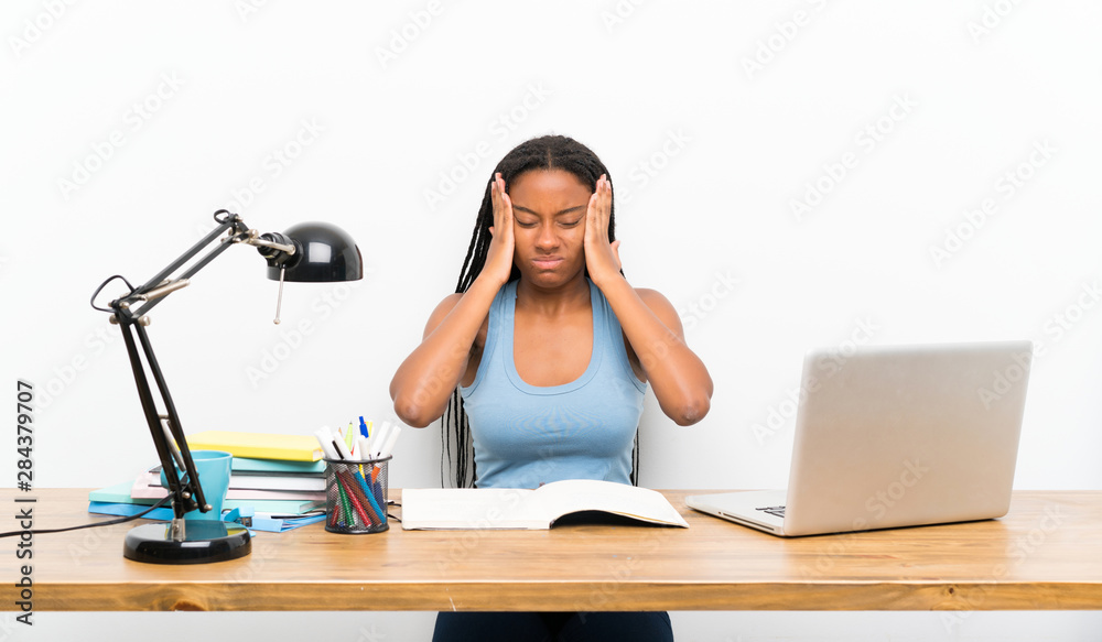 African American teenager student girl with long braided hair in her workplace with headache African American teenager student girl with long braided hair in her workplace with headache
