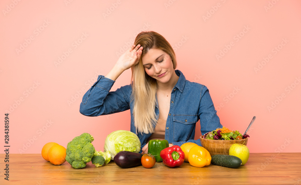 Young blonde woman with many vegetables with tired and sick expression Young blonde woman with many vegetables with tired and sick expression