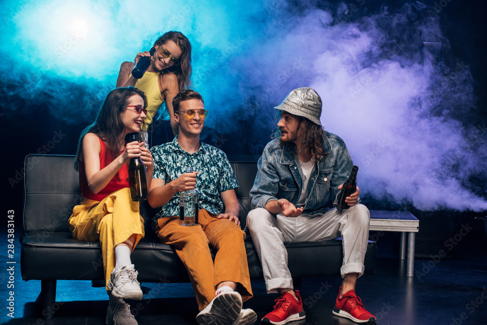 happy young women and men with alcohol sitting on couch in nightclub happy young women and men with alcohol sitting on couch in nightclub