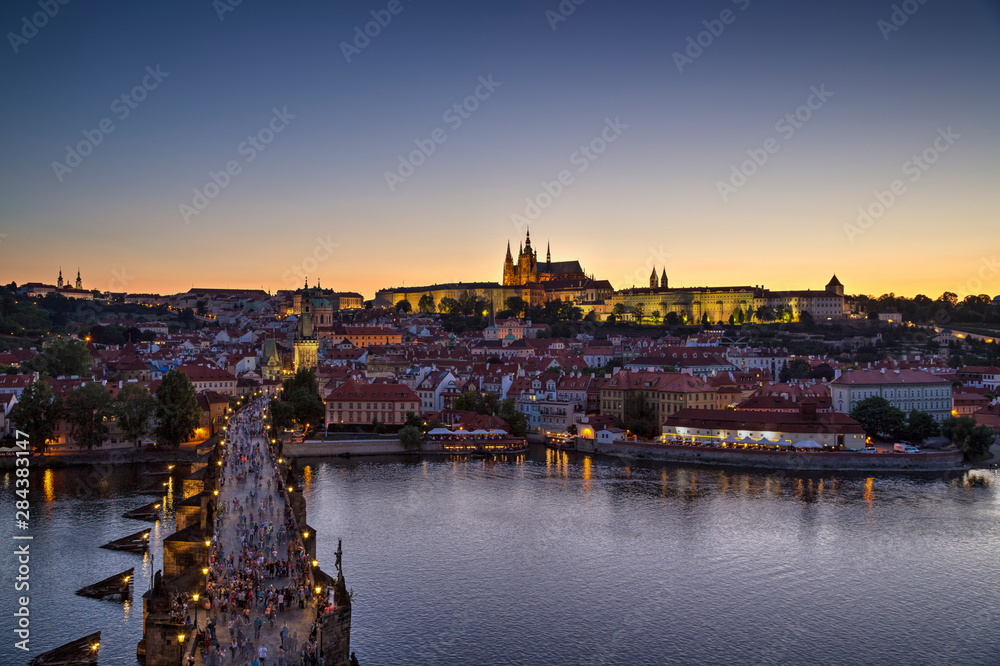 View of the crowded Charles Bridge (Karluv most) over Vltava River, Mala Strana district and illuminated Prague (Hradcany) Castle in Prague, Czech Republic, in the evening. Copy space.