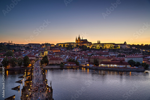 View of the crowded Charles Bridge (Karluv most) over Vltava River, Mala Strana district and illuminated Prague (Hradcany) Castle in Prague, Czech Republic, in the evening. Copy space.