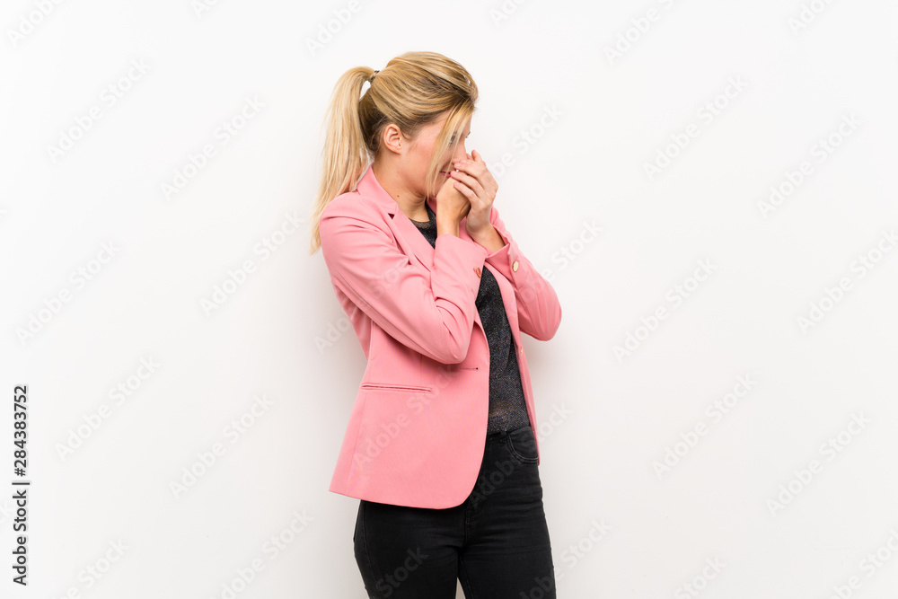Young blonde woman with pink suit covering mouth and looking to the side Young blonde woman with pink suit covering mouth and looking to the side