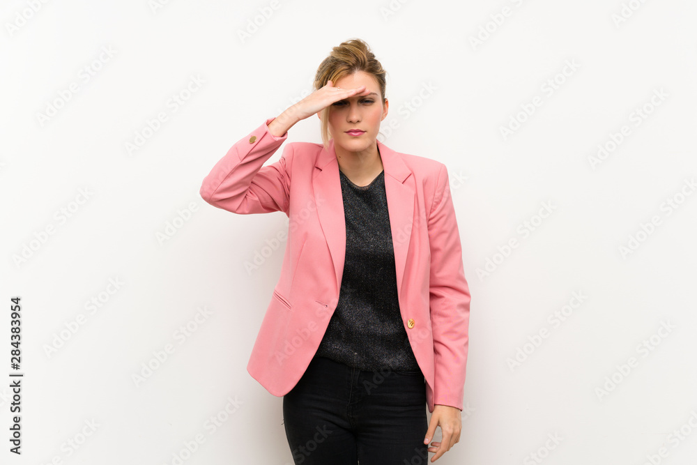 Young blonde woman with pink suit looking far away with hand to look something Young blonde woman with pink suit looking far away with hand to look something