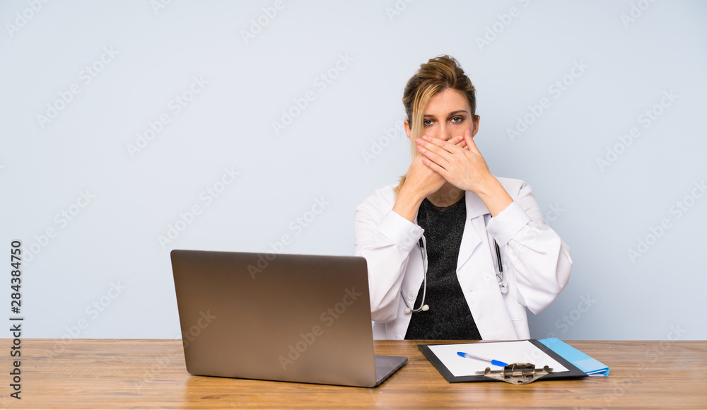 Blonde doctor woman covering mouth with hands Blonde doctor woman covering mouth with hands