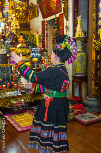 Woman in traditional dress performing ceremony in temple, Hanoi, Vietnam