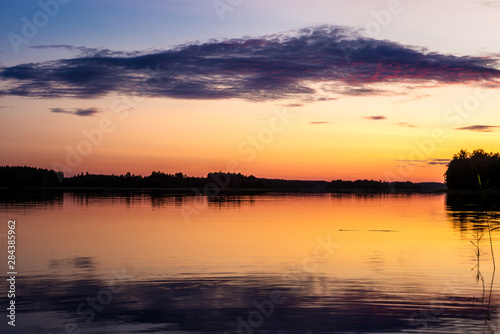 Violet clouds at sunset on the shores of the calm Saimaa lake in the Linnansaari National Park in Finland