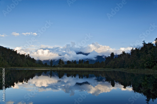 New Zealand, South Island. Cloud-shrouded Southern Alps seen from Lake Matheson. 