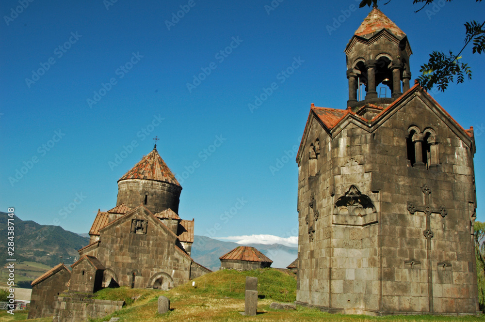Armenia, Haghpat, view of a catholic church built with stones, and an orange tiled roof, with mountains in the background against clear sky