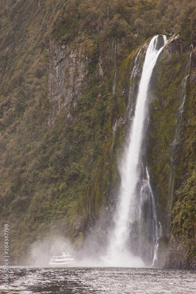 Fototapeta premium South Pacific, New Zealand, South Island, Fiordland National Park. A tourist boat moves close to Stirling Falls. 