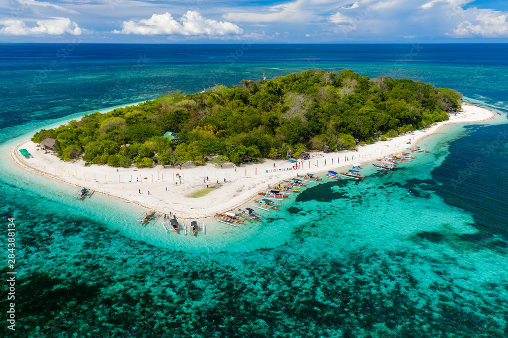 Aerial drone view of a beautiful tropical island surrounded by coral reef (Mantigue Island, Camiguin, Philippines)