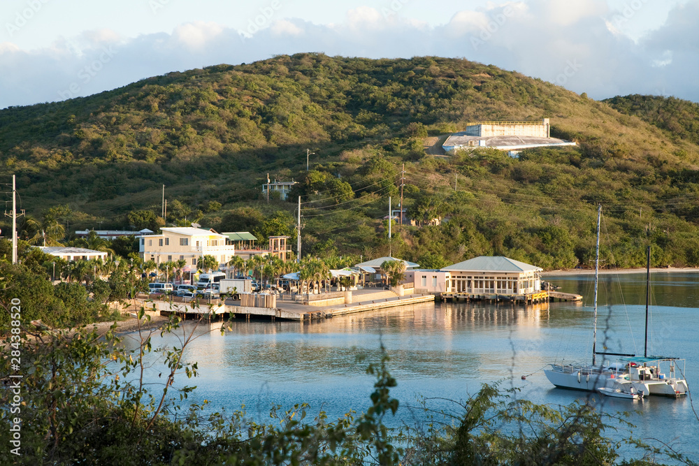 Vieques, Puerto Rico - A seaside marina is set in the waters of a calm ocean bay. In the foreground a sailboat can be seen anchored in the bay.