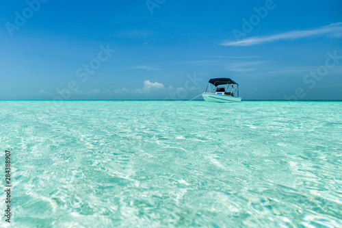 A boat is anchored over a shallow sandbar in clear waters near Staniel Cay, Exuma, Bahamas