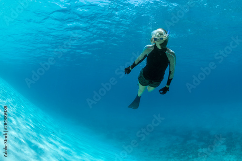 Woman snorkeling beneath the surface in the ultra-clear and blue waters of Staniel Cay, Exuma, Bahamas