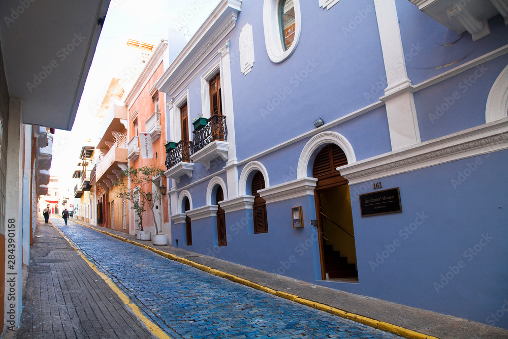 San Juan, Puerto Rico - Two people are walking up a sloped brick lane in an old world section of the city. The brick road is painted blue.