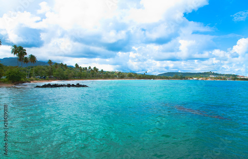 San Juan, Puerto Rico - Calm water is seen in the bay of a tropic island. Trees and beach can be seen in the background.