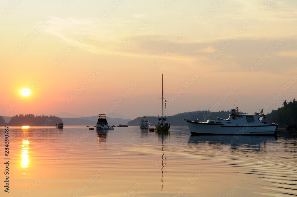 Canada, British Columbia, Gulf Islands, Wallace Island. Yellow sunset with anchored boats in Princess Bay