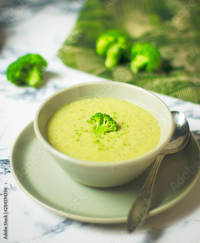 Fresh Broccoli cream soup on two gray ceramic bowl on plate with spoon on marble background,vegetarian food,healthy concept