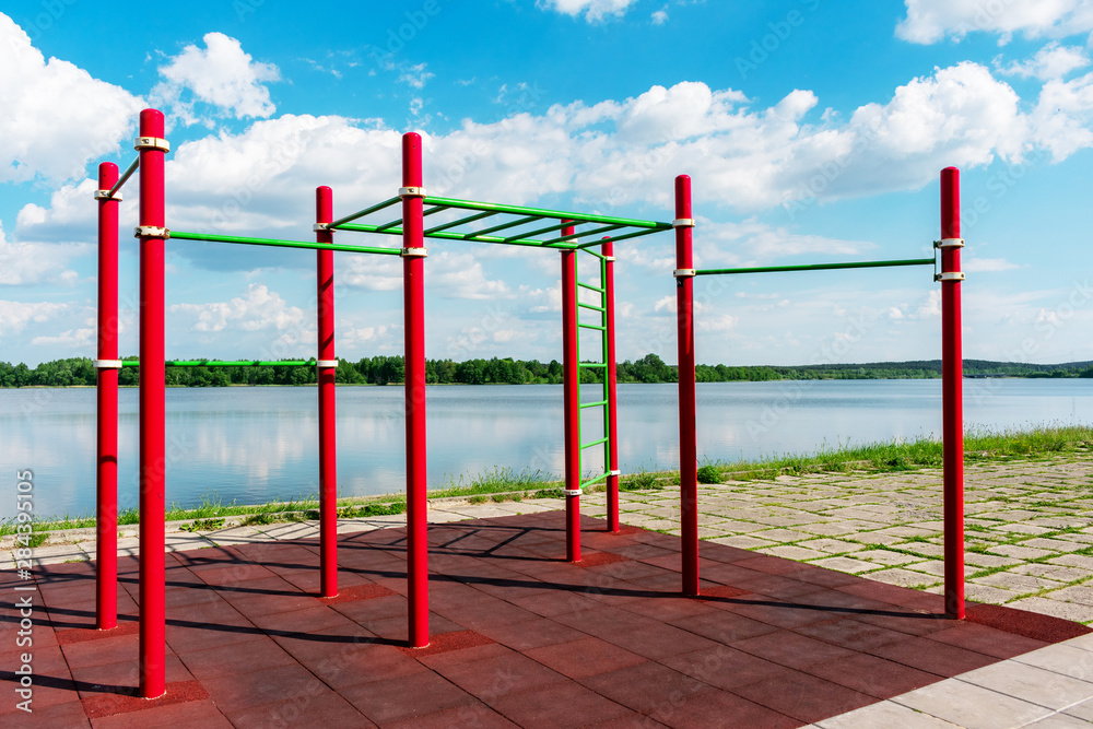 Red horizontal bars against a blue cloudy sky in summer park, outdoors