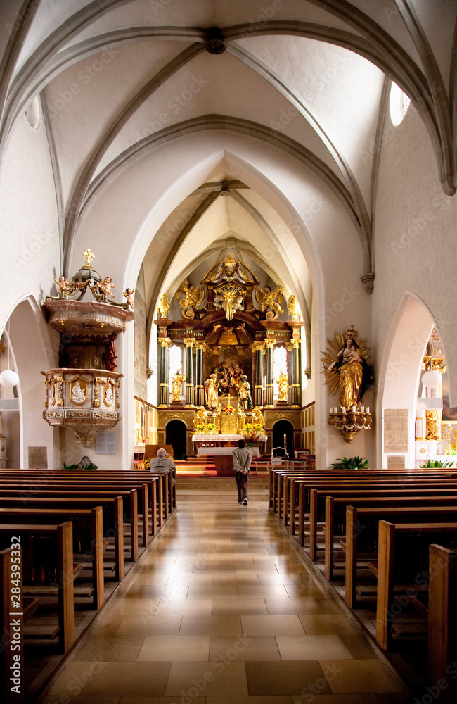 Wels, Upper Austria, Austria - Looking down the center aisle of a Gothic style church with two people in the sanctuary.