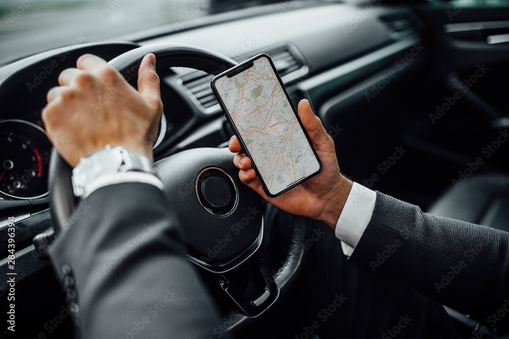 Man in the car holding smart phone with gps map navigation. Close up. Man in the car holding smart phone with gps map navigation. Close up.