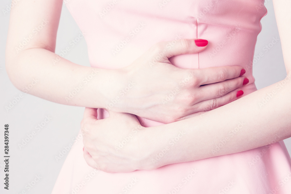The woman has a stomach aches, ulcer or gastritis, female hands, close up, cropped image, toned The woman has a stomach aches, ulcer or gastritis, female hands, close up, cropped image, toned