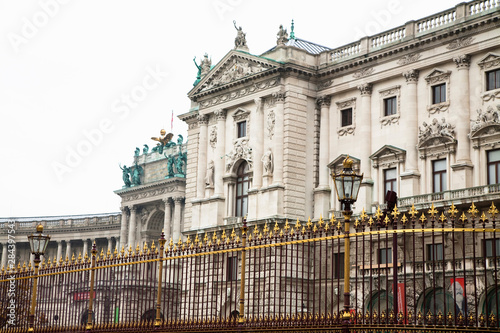 Austria, Vienna. Low angle view of an old world building surrounded by and ornate, wrought-iron fence.