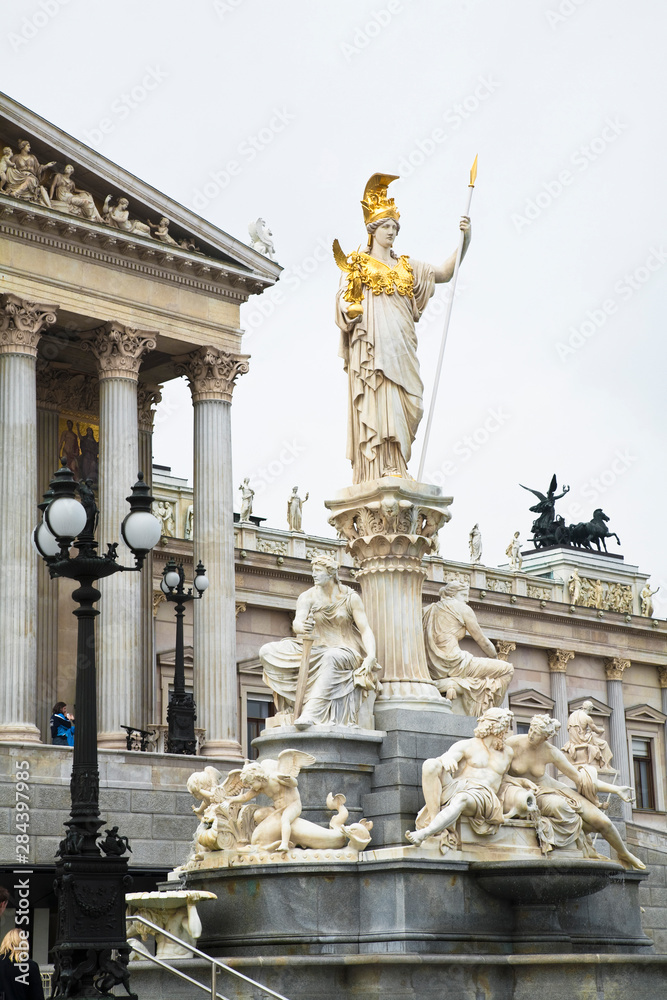 Obraz premium Austria, Vienna. A romanesque statue stands on a dry water feature in front of a building with columns.