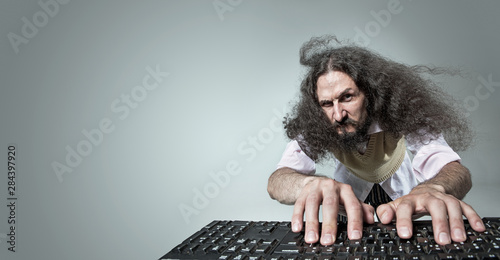 Funny portrait of a skinny nerd working with a computer photo
