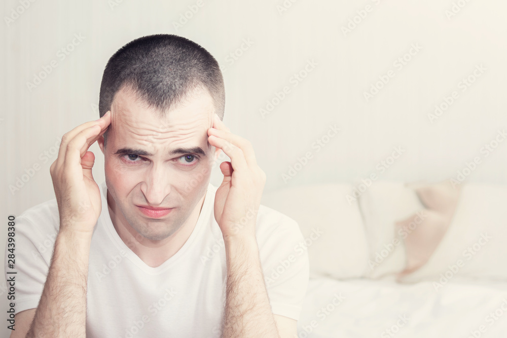 A man in the bedroom, unhappy man sitting on the bed holding his head, toned, the concept of problems in sex A man in the bedroom, unhappy man sitting on the bed holding his head, toned, the concept of problems in sex