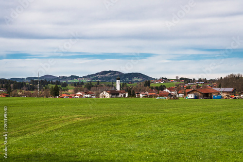 Village across a field with a typical Bavarian church nestled in the hills in Germany