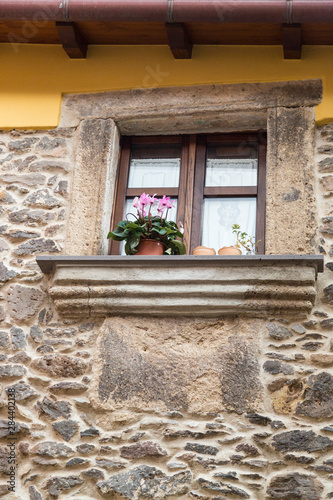 Italy, Sardinia, Santu Lussurgiu. Plants sitting the windowsill of a stone walled building. photo