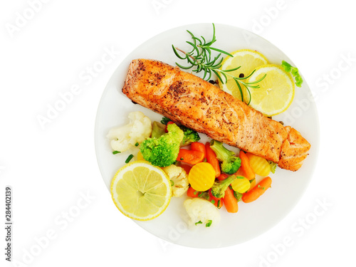 Grilled salmon fillet with vegetables, lemon and rosemary over white plate isolated, top view, overhead.