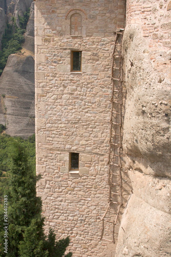 Greece, Meteora. Escape ladder and chain against stone wall at Saint Barbara Roussanou Monastery. Greece, Meteora. Escape ladder and chain against stone wall at Saint Barbara Roussanou Monastery.