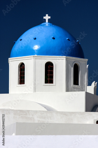Oia, Island of Santorini, Greece. Blue Orthodox Church Dome, Cross, and a White Washed Building,