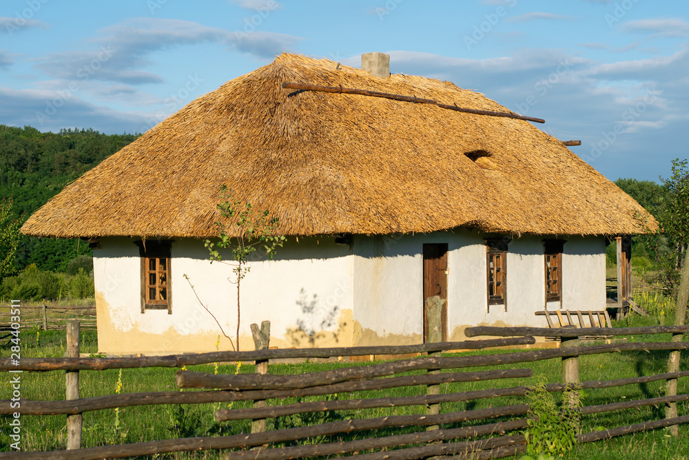 Traditional Ukrainian house. Window and door in a wooden frame. Roof made of straw