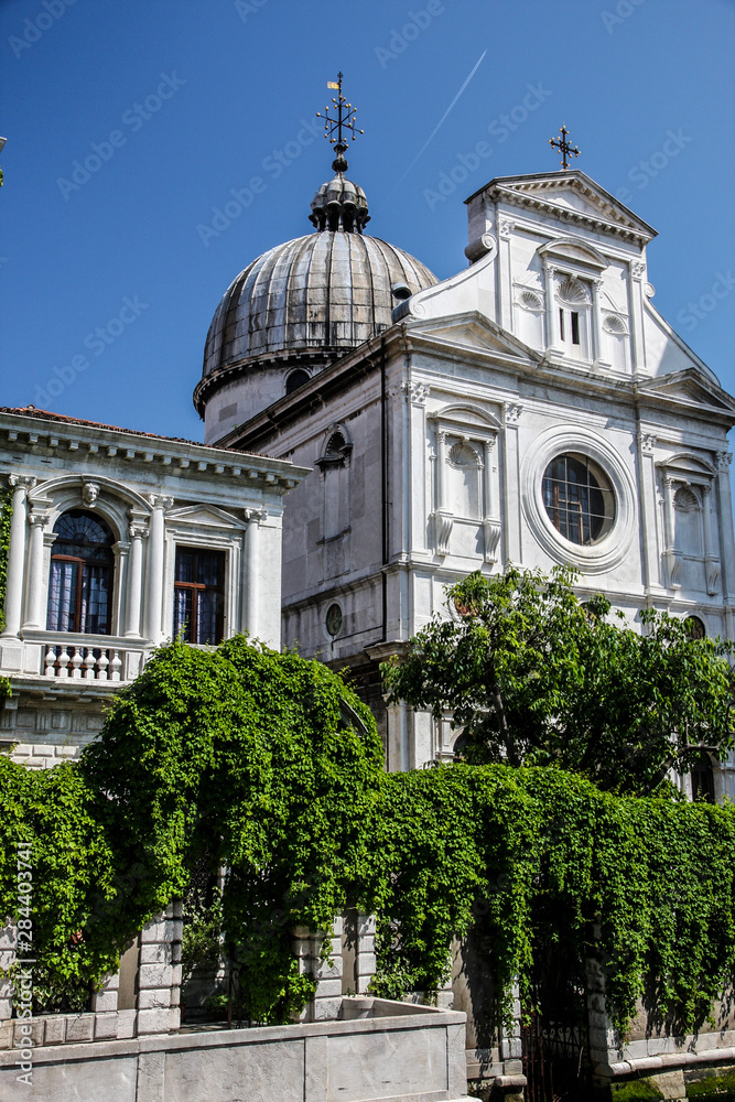 Venice, Italy. Venetian church, with cross and onion dome, with ivy, along the canal
