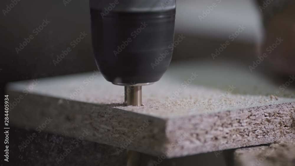 Woodworker drilling wood with electric hand drill. Close-up view.