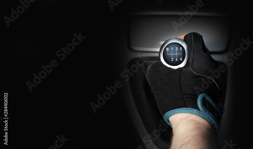 Dłoń w rękawiczce na sześcio biegowej dźwigni zmiany biegów w samochodzie osobowym, tekst.