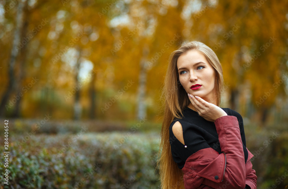 Elegant blonde girl posing at the autumn forest