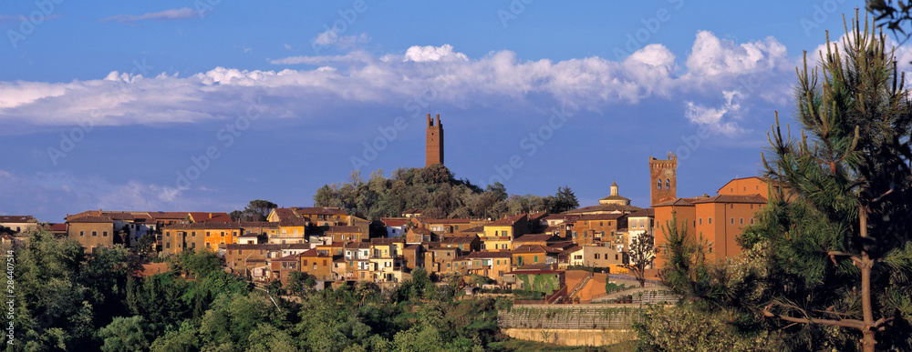 Italy, San Miniato. Beneath a wide, blue sky, the sienna tones of San Miniato spread and glow, in Tuscany, Italy.
