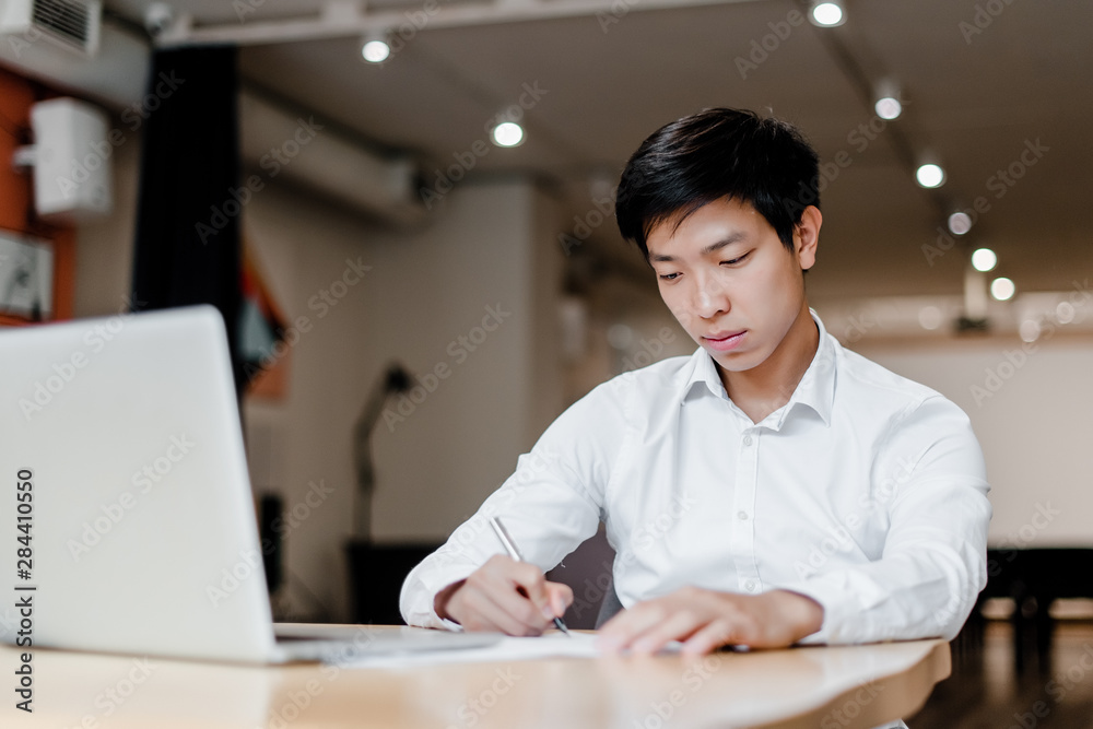 asian man in the office uses laptop