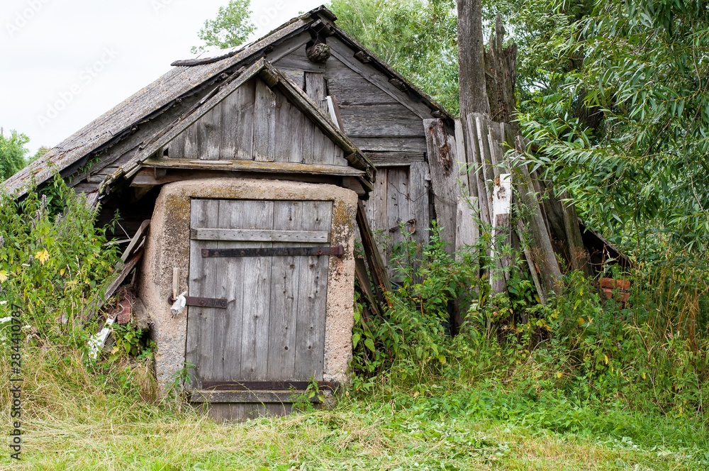 Wooden abandoned farmhouse with peeling paint and broken windows in rural countryside in summer Wooden abandoned farmhouse with peeling paint and broken windows in rural countryside in summer