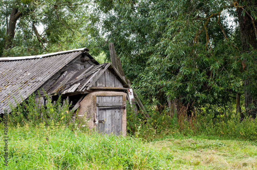 Wooden abandoned farmhouse with peeling paint and broken windows in rural countryside in summer Wooden abandoned farmhouse with peeling paint and broken windows in rural countryside in summer