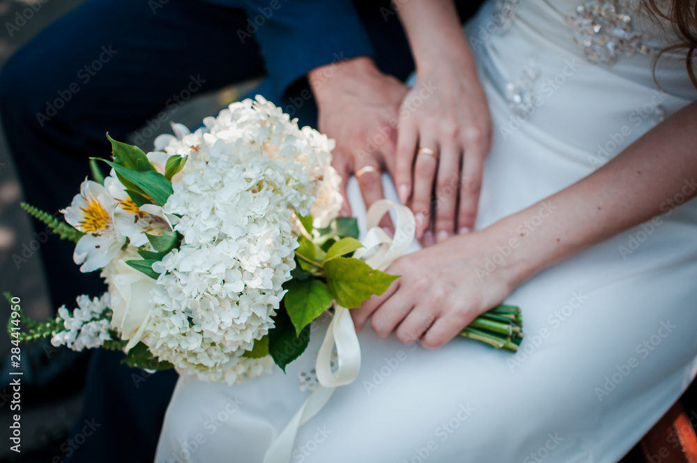 Bride and groom hands with flower bouquet in the hands Bride and groom hands with flower bouquet in the hands