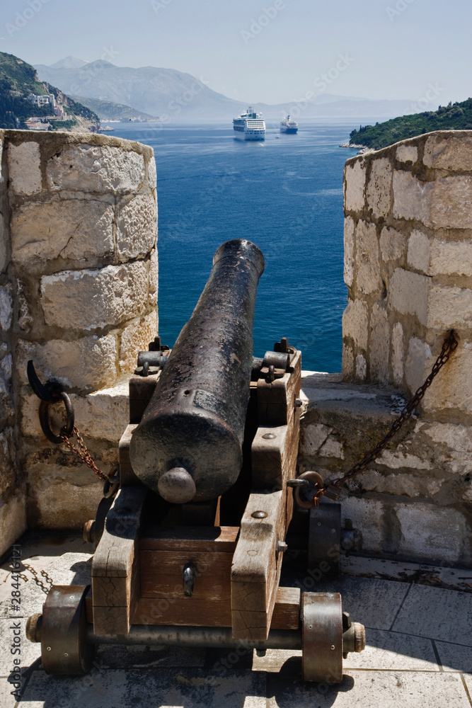 Old Cannon seemingly aimed at modern cruise ship docked in harbor at Old Town Dubrovnik a UNESCO World Heritage Site, Croatia Old Cannon seemingly aimed at modern cruise ship docked in harbor at Old Town Dubrovnik a UNESCO World Heritage Site, Croatia