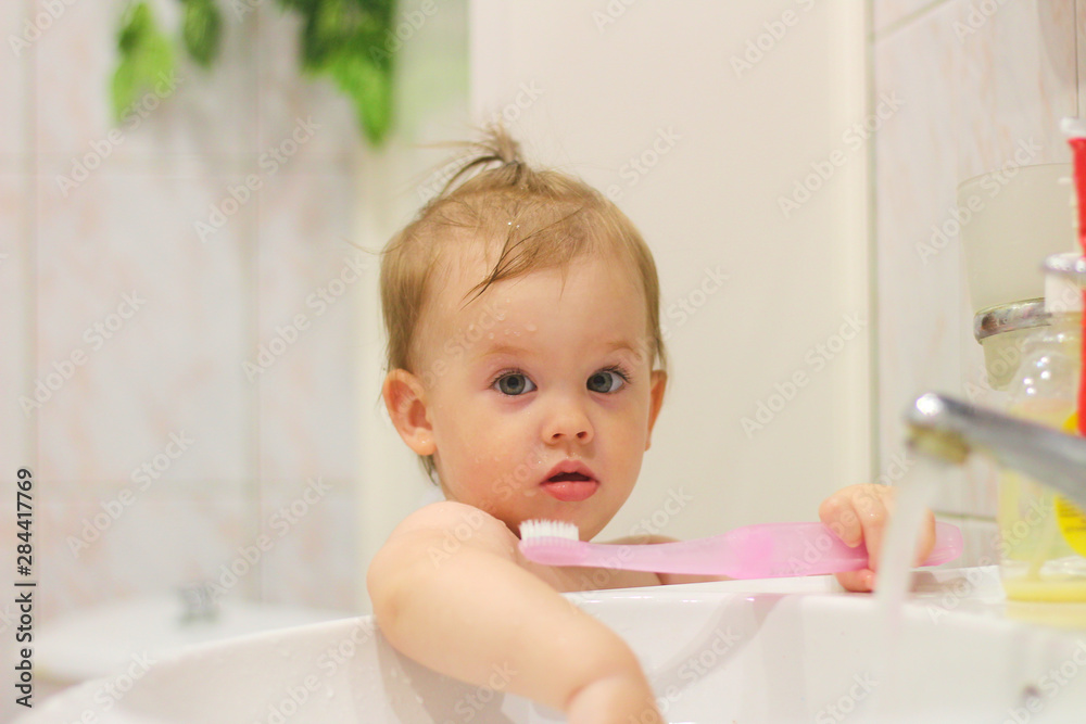 cute little white child with a tail brushes his teeth near the washbasin cute little white child with a tail brushes his teeth near the washbasin
