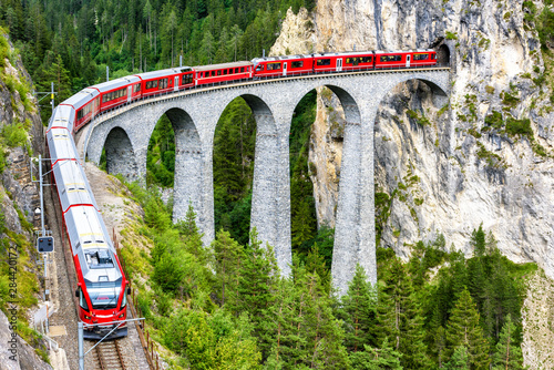 Red express train on Landwasser Viaduct, Switzerland. Railway of Swiss mountains.