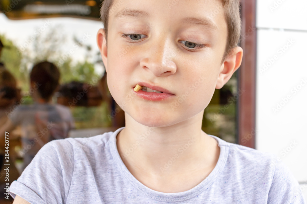 A hungry boy eating a fried potatoes on the summer terrace of the city fast food restaurant, close up view A hungry boy eating a fried potatoes on the summer terrace of the city fast food restaurant, close up view