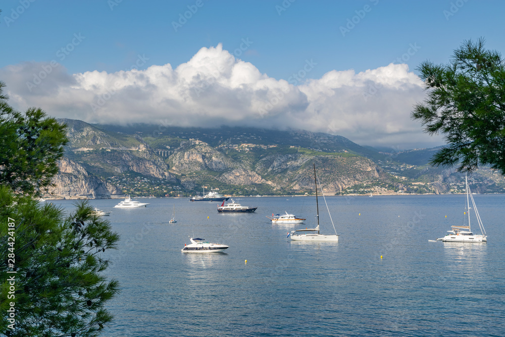 Bay with floating yachts on the horizon mountains, blue sky with clouds. Sunny day, French